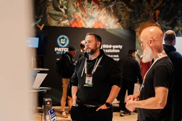 A sponsor in conversation with an attendee at their booth during Workplace Ninjas Norway 2026
